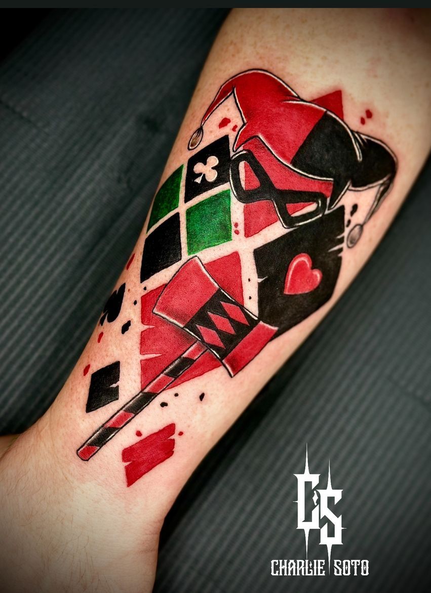 Harley Quinn tattoo with red, black, and green diamond suit cards and a jester hat.