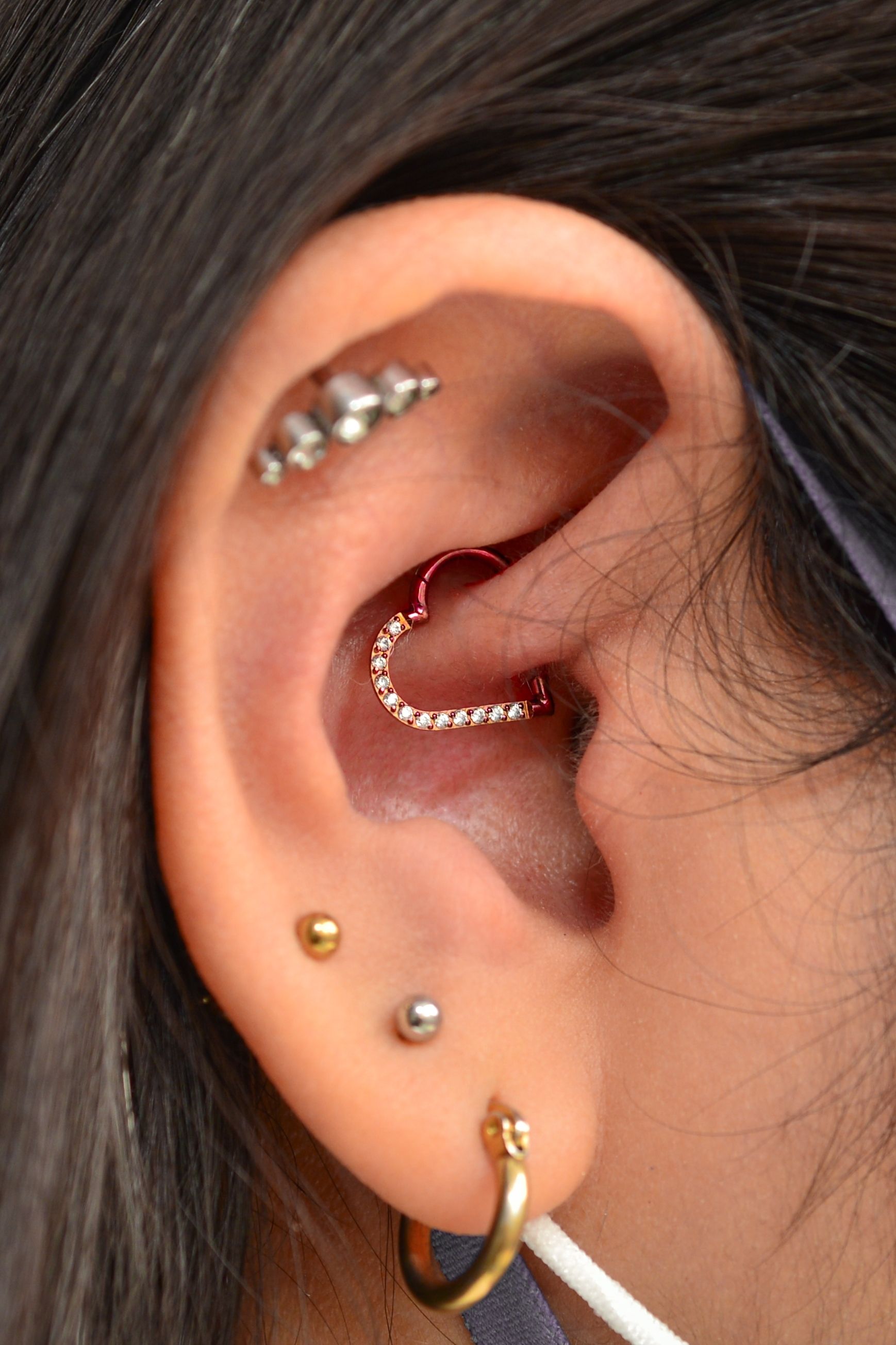 A close up of a woman 's ear with multiple piercings