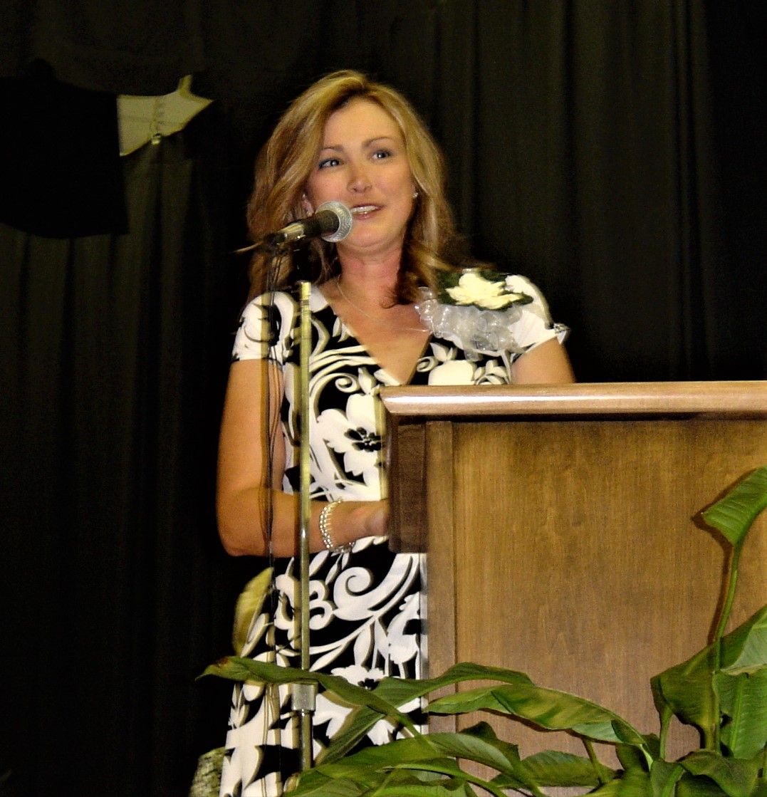 a woman in a black and white dress is speaking into a microphone