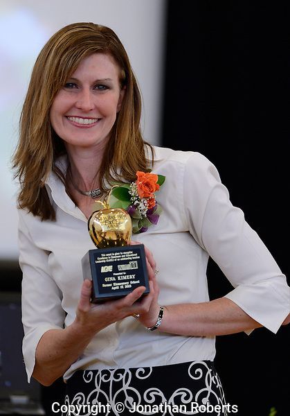 a woman in a white shirt is holding a trophy
