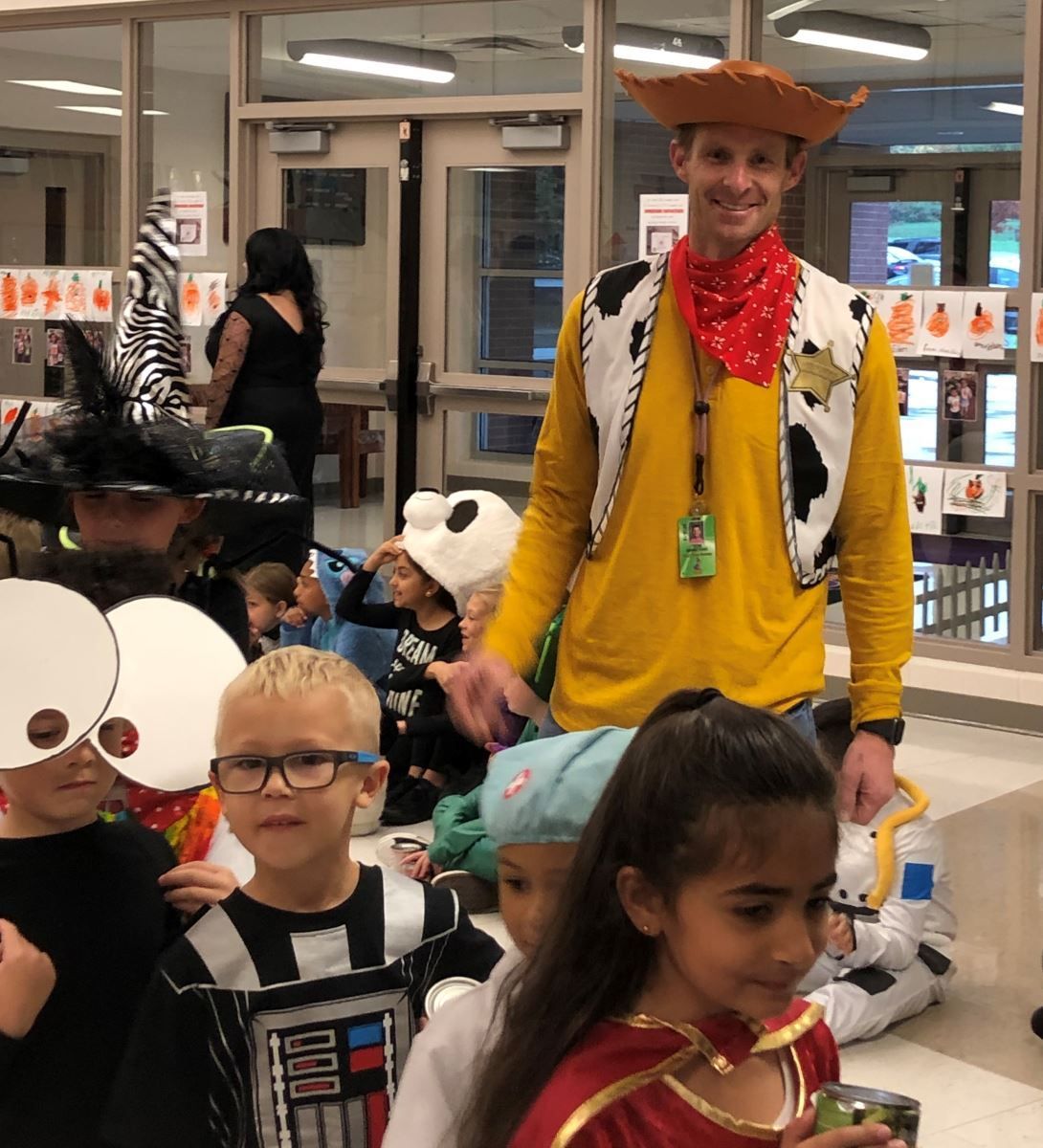 a man in a cowboy hat is standing next to a group of children in costumes
