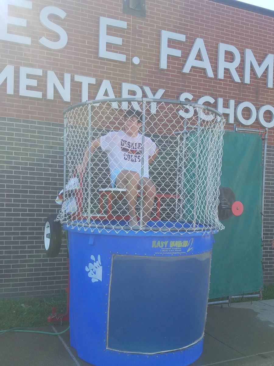 a boy is sitting in a dunk tank in front of the es e farm elementary school