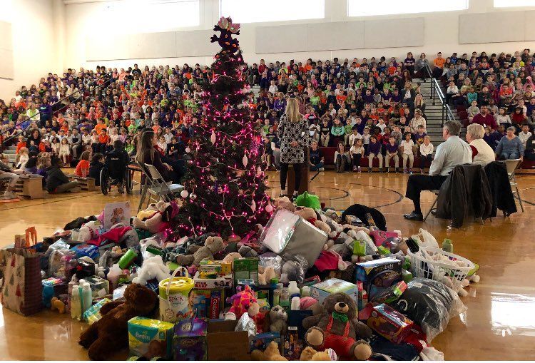 a christmas tree is surrounded by lots of toys in a gym .