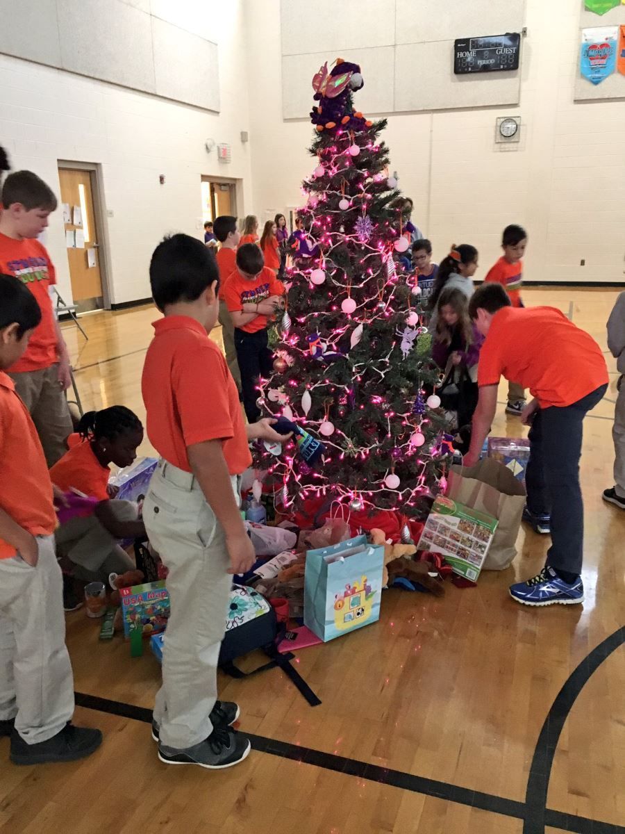 a group of children are decorating a christmas tree in a gym .