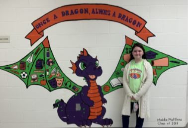 a girl stands in front of a mural of a dragon that says once a dragon always a dragon
