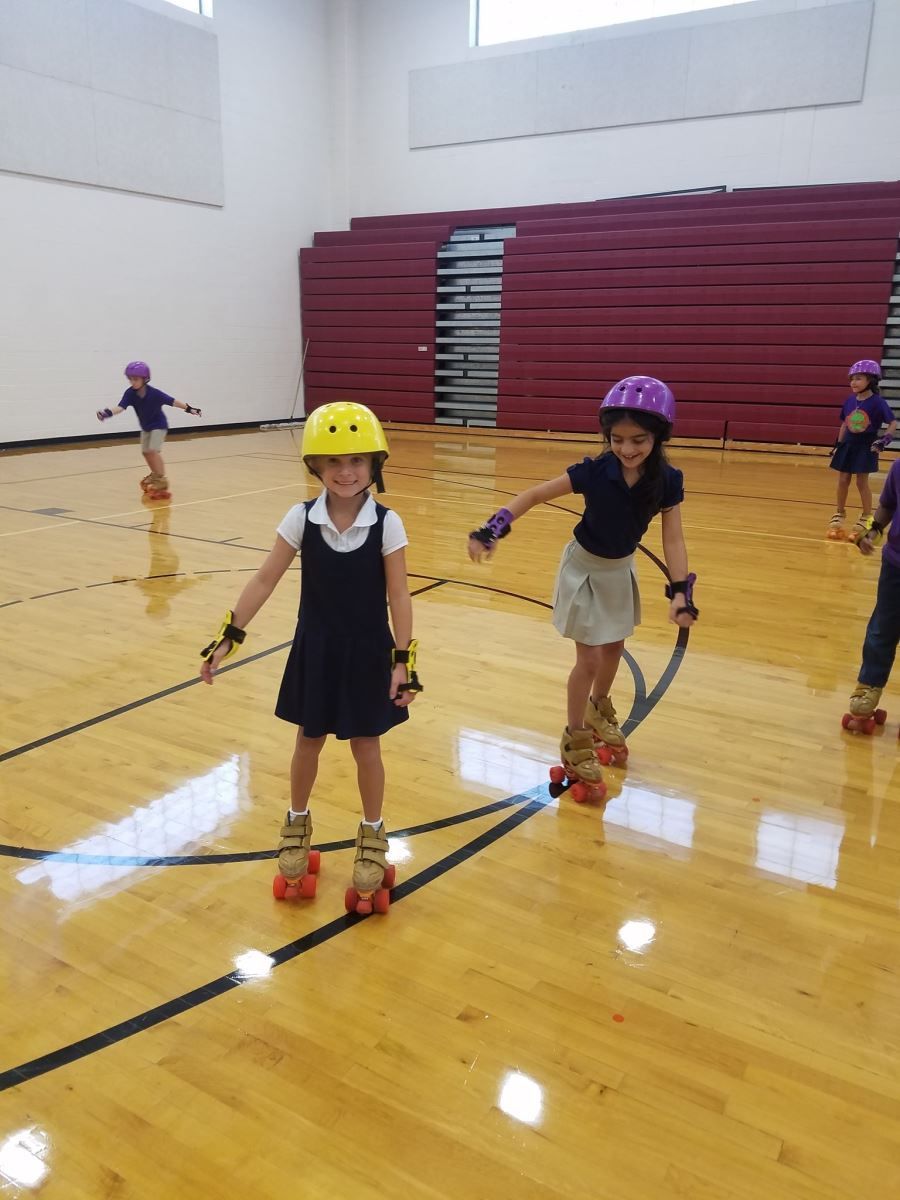 a group of young girls are rollerblading in a gym .