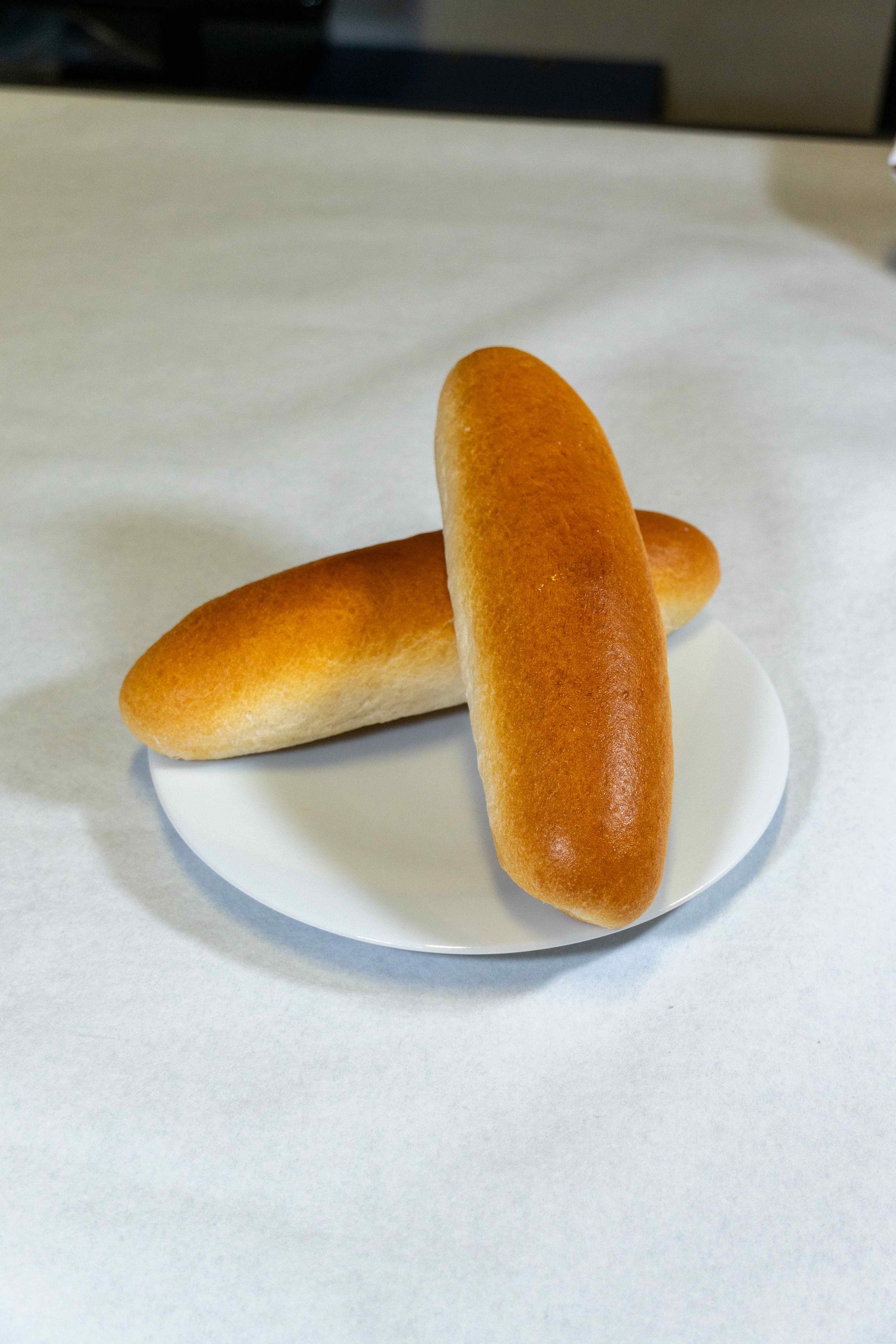 Deux pains à hot-dog sur une assiette blanche sur une table
