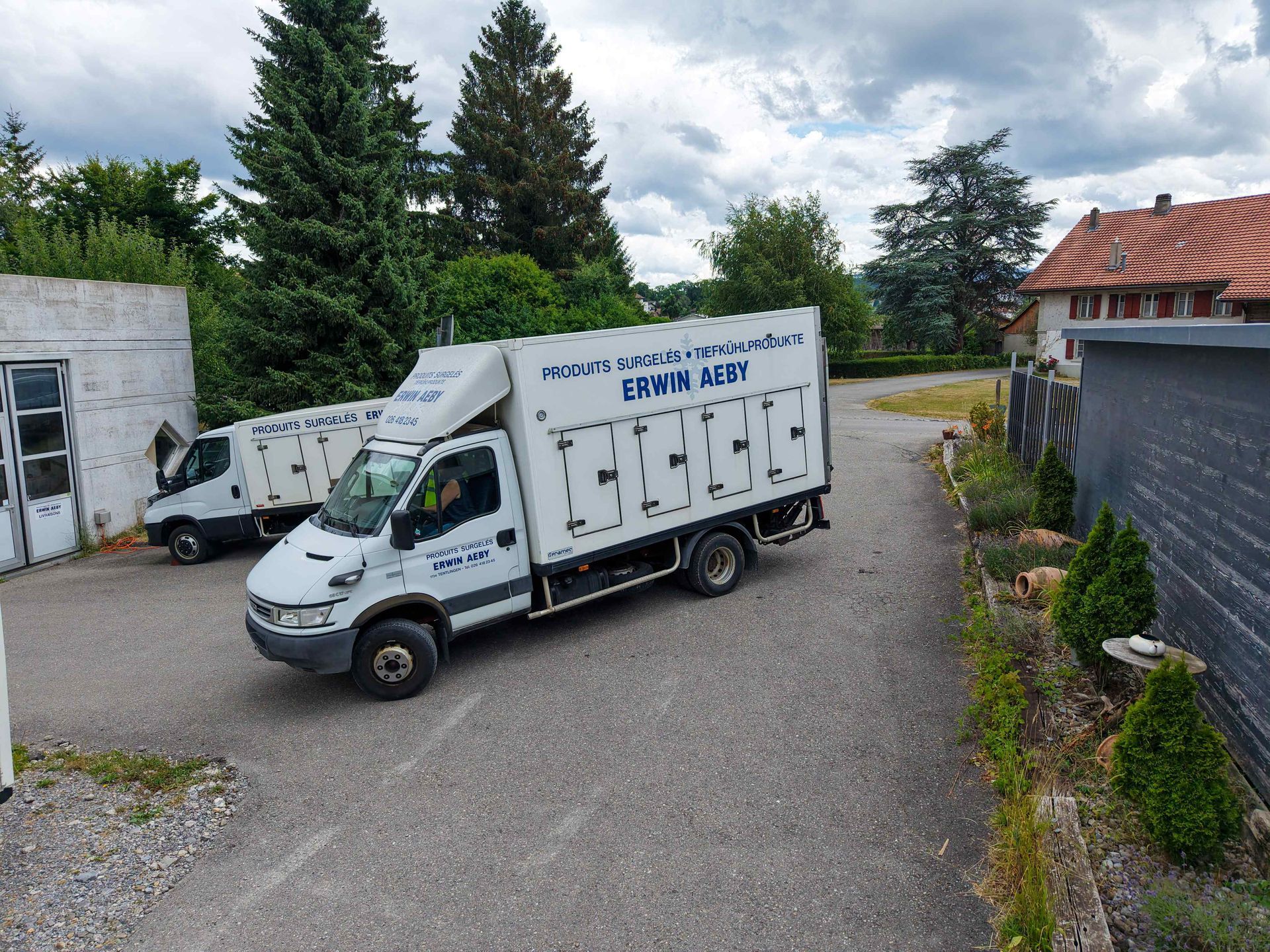 Deux camions blancs sont garés l'un à côté de l'autre sur un parking.