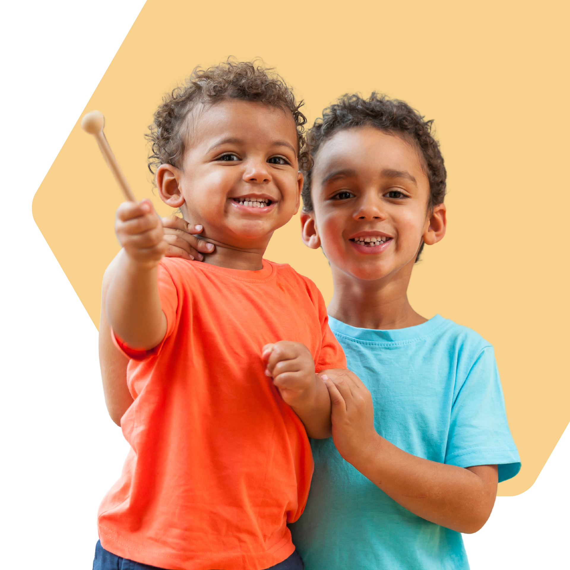 Two young boys smiling, one holding a drumstick, orange and blue shirts, on a yellow background.