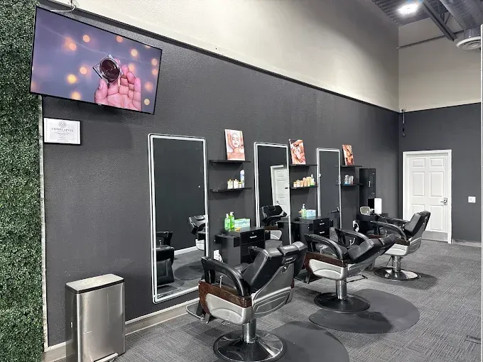 Hair salon interior with dark gray walls, mirrors, chairs, and a TV.