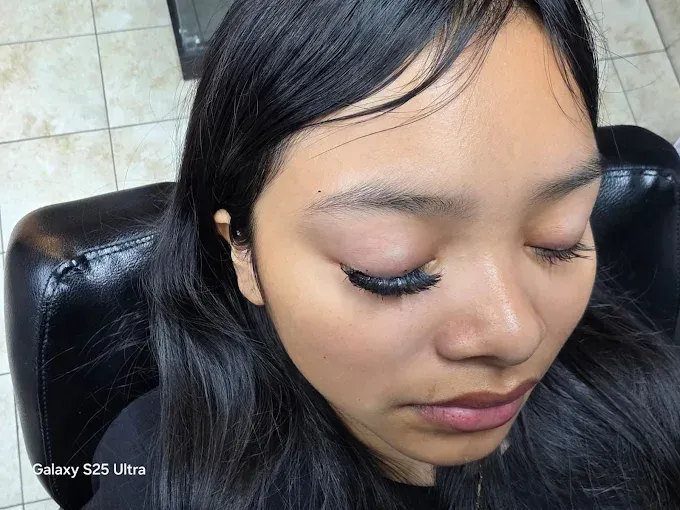 Woman with long, dark eyelashes. She is sitting with her eyes closed, dark hair.