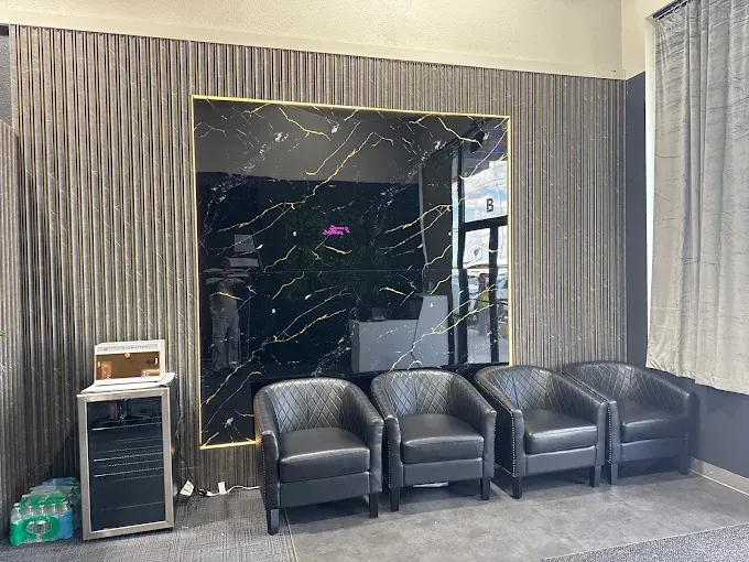 Waiting area with black leather chairs, marble-look wall, and curtains.