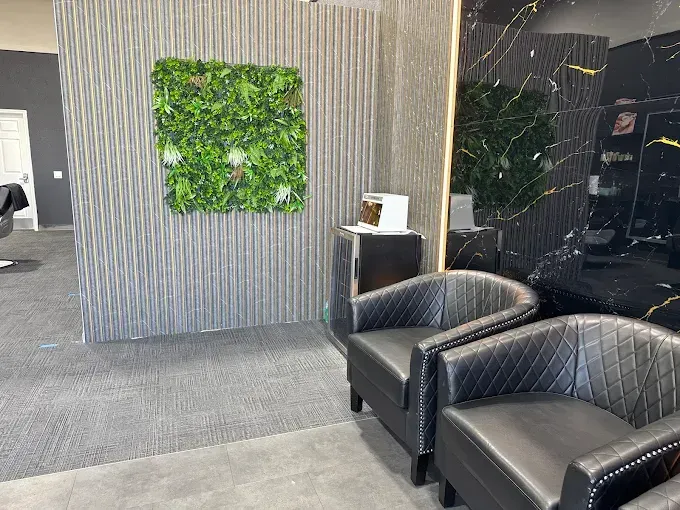 Two black armchairs in a modern waiting area with a moss wall decor and textured gray wall.
