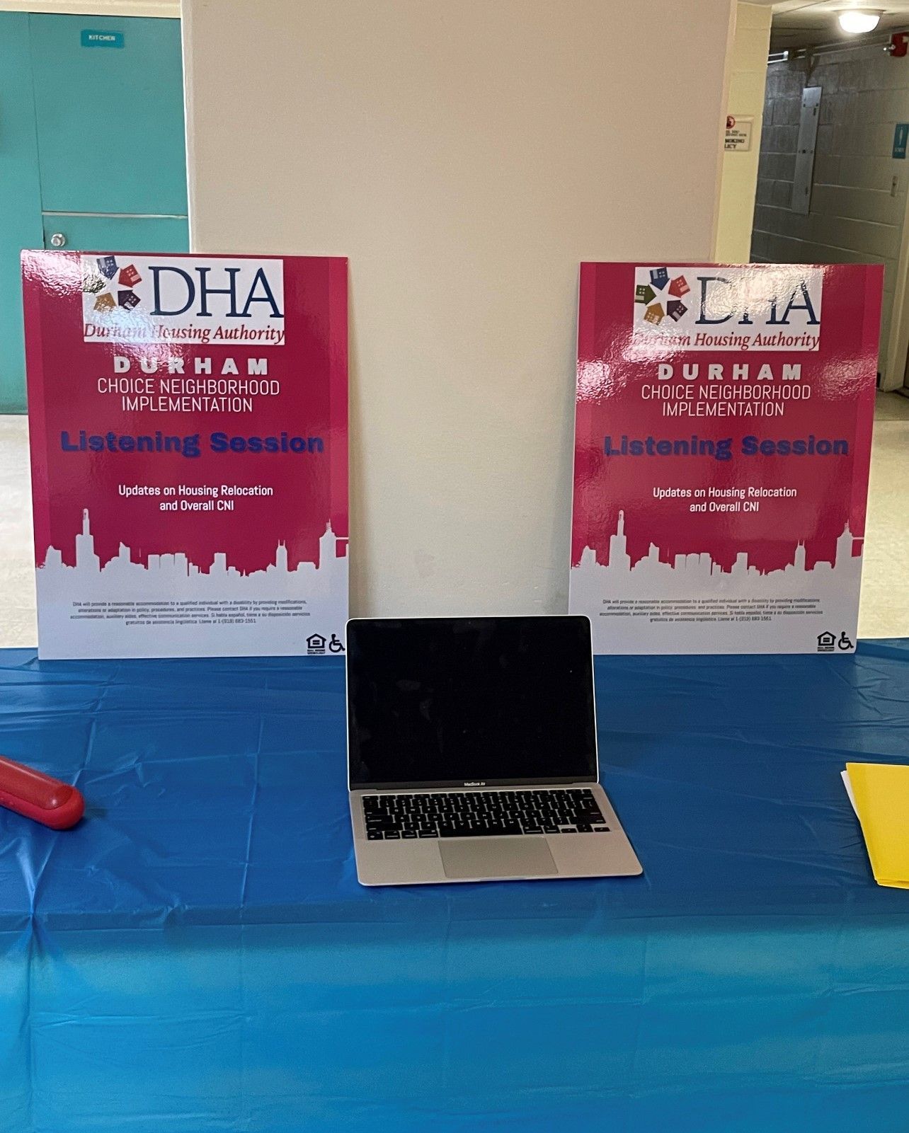 A laptop sits on a table next to a sign that says dha