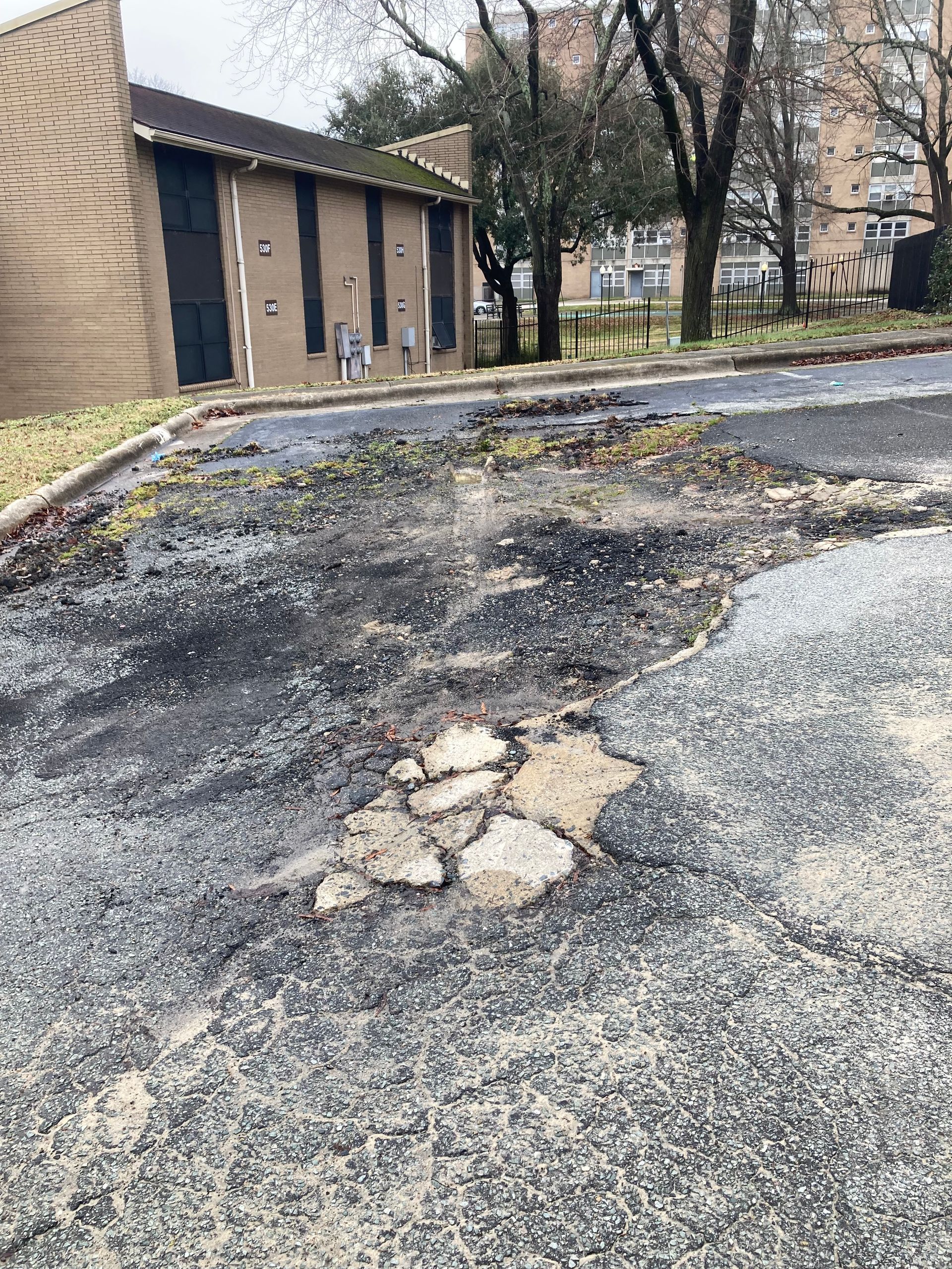 A very dirty parking lot with a building in the background.