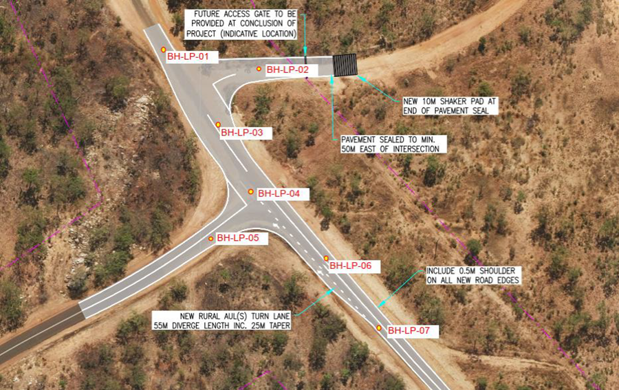 An aerial view of a road intersection with trees and dirt.