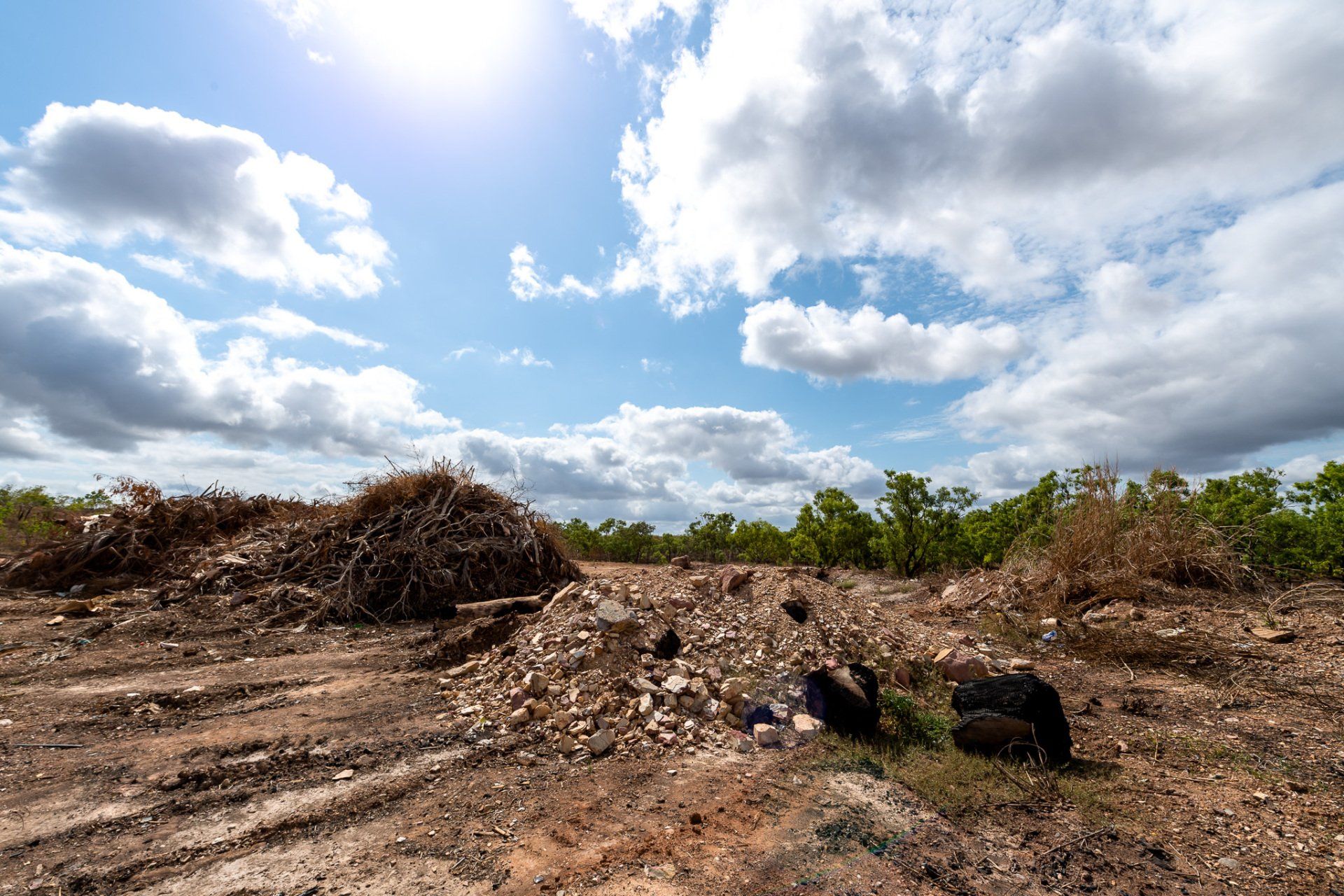 A pile of wood is sitting in the middle of a dirt field.
