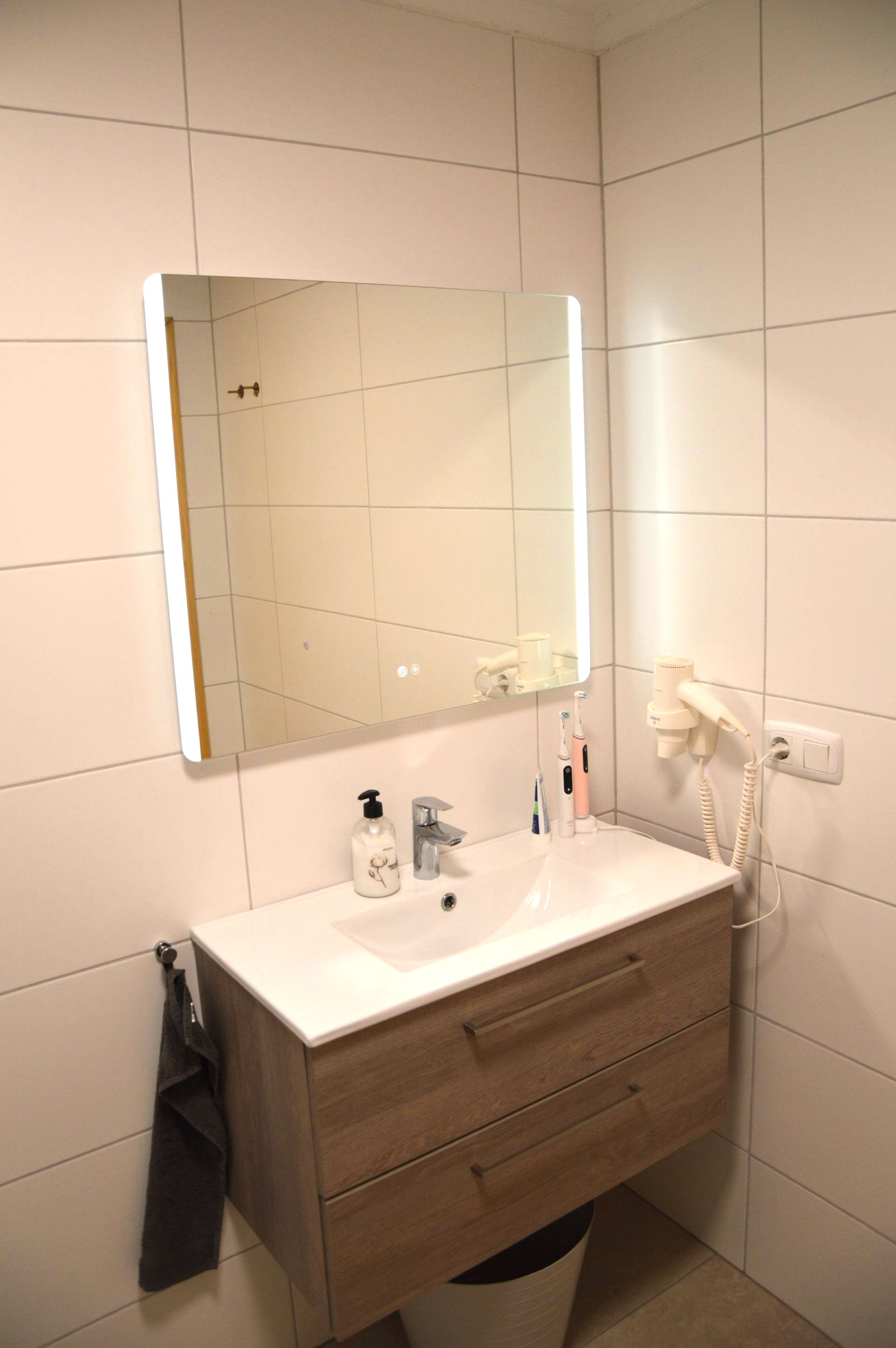 Een badkamer met wastafel, spiegel en föhn.