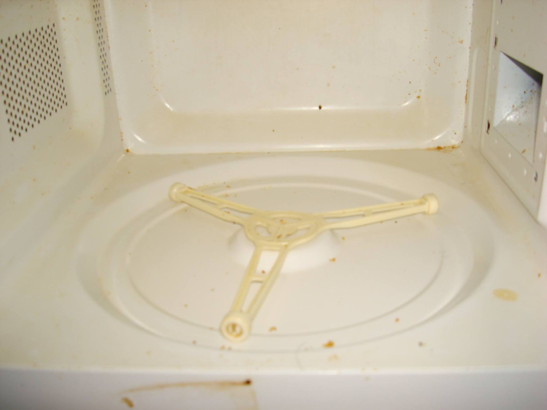 The inside of a dirty microwave with a white tray