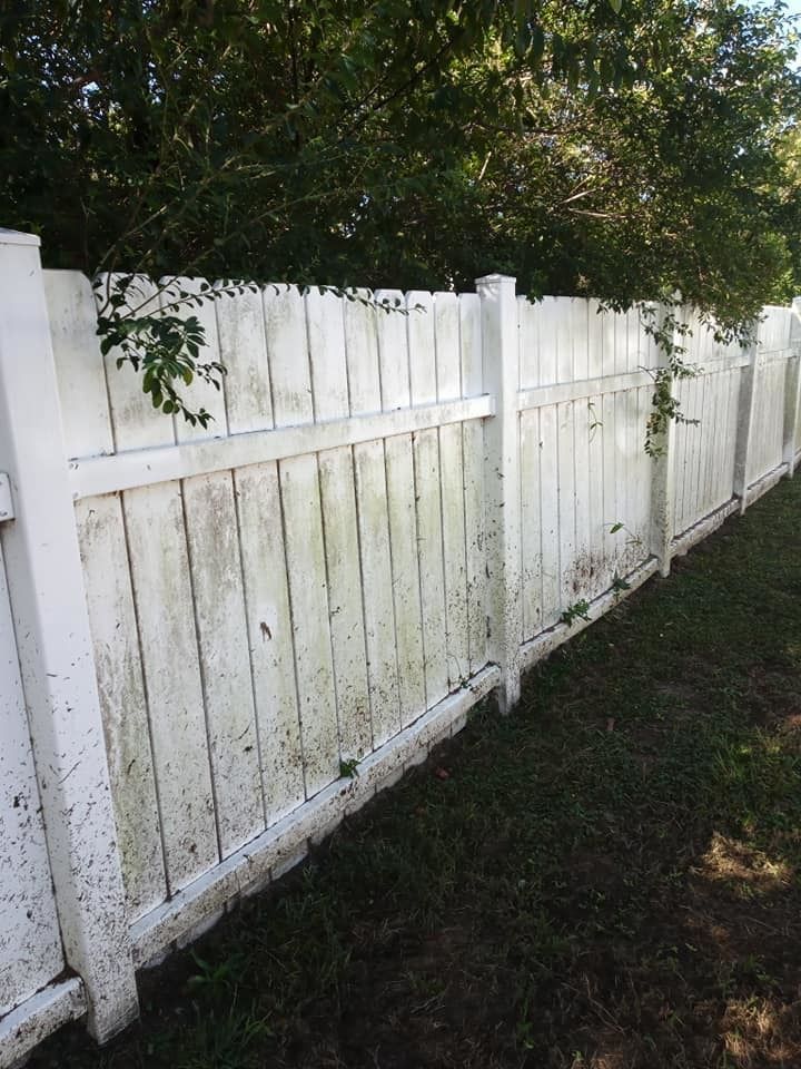 A dirty white wooden fence is sitting in the grass.