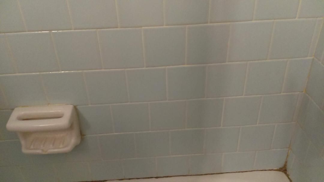 A bathroom with blue tiles and a soap dish on the wall.