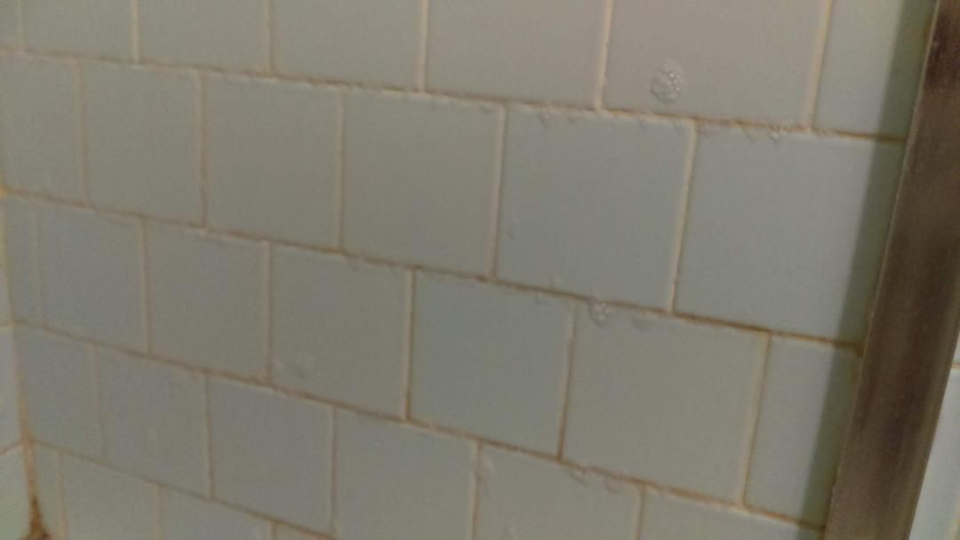 A close up of a white tiled wall in a bathroom.