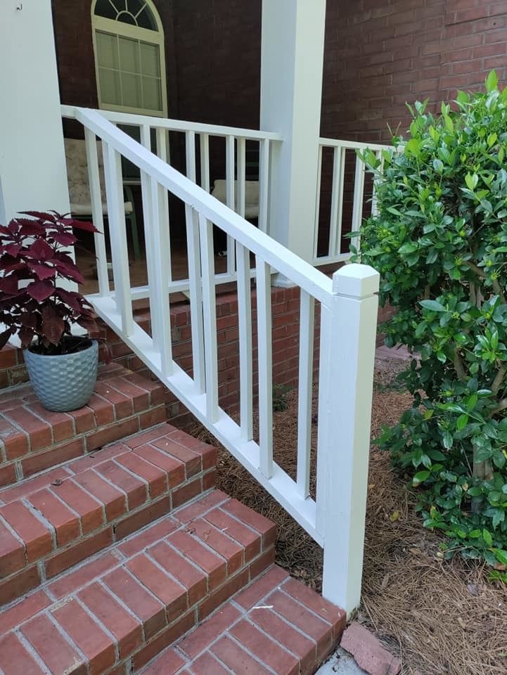 A white railing on a brick porch next to a potted plant.