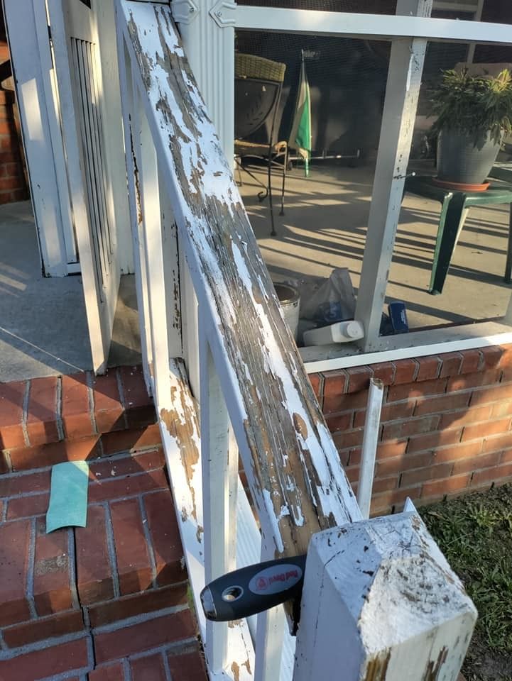A white railing with peeling paint is sitting on a brick porch.