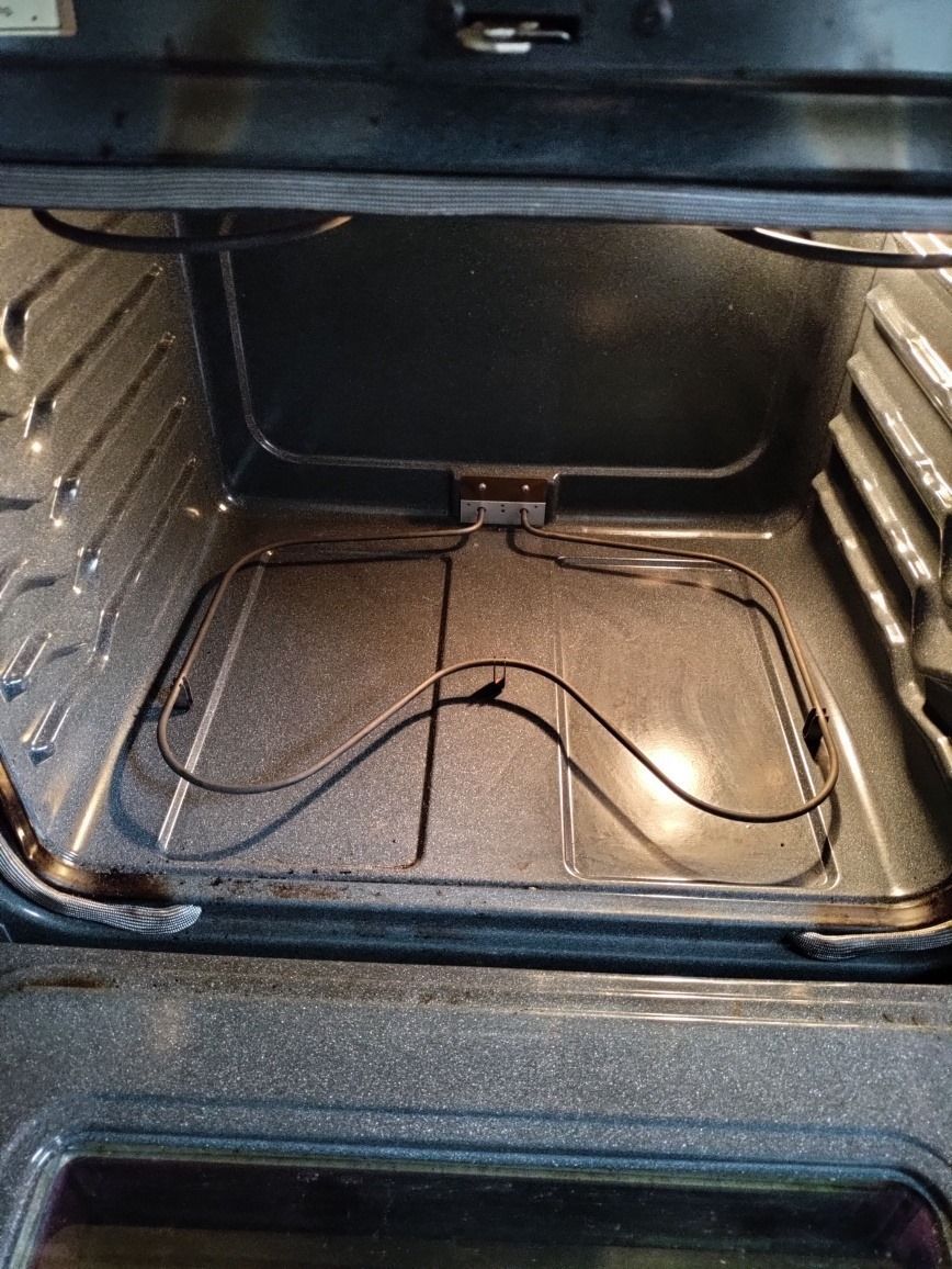 The inside of an oven with a wire coming out of it.