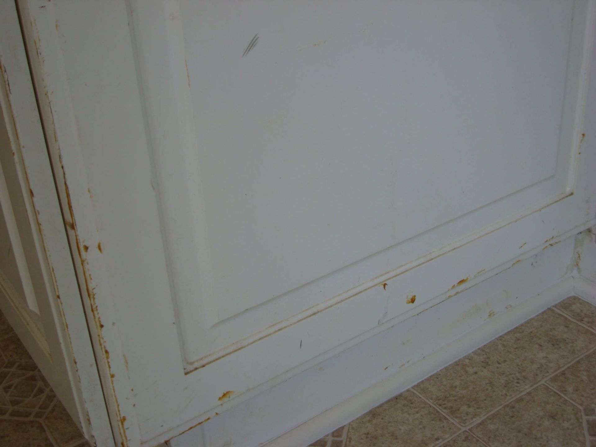 A close up of a white cabinet with rust on it.