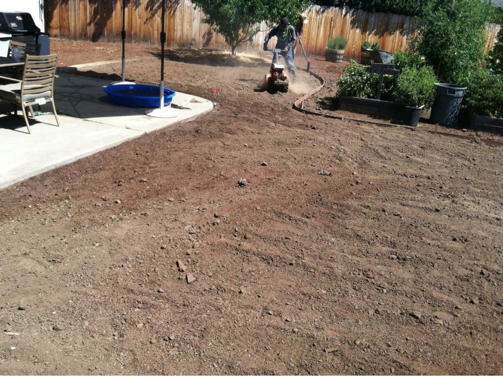 A Man Is Riding a Lawn Mower in A Backyard - Oroville, CA - JR Landscaping 