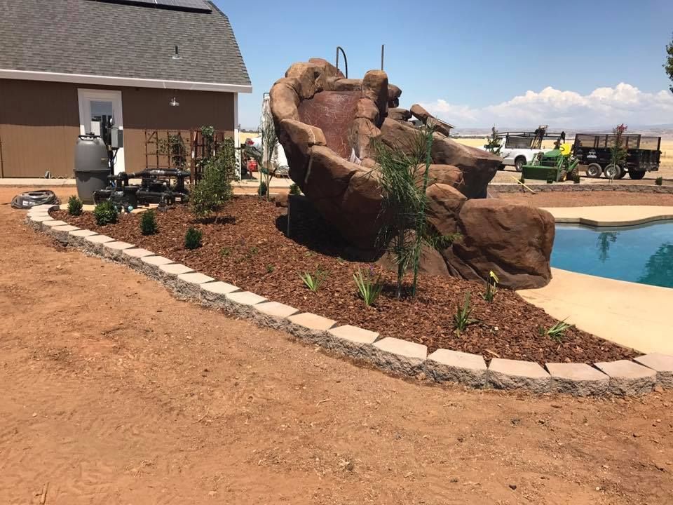 A Swimming Pool With A Waterfall and A House in The Background - Oroville, CA - JR Landscaping 