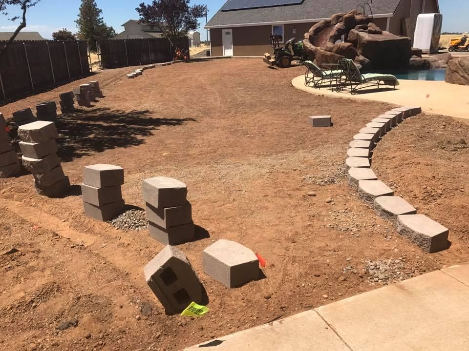 A Row of Bricks Are Sitting in The Dirt in Front of A House - Oroville, CA - JR Landscaping 
