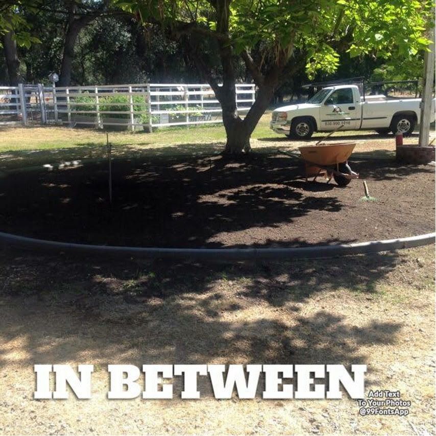 A Wheelbarrow Sits in The Middle of A Dirt Field with The Words in Between Above It - Oroville, CA - JR Landscaping