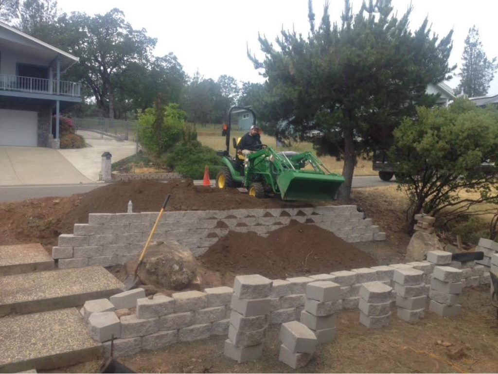 A Man Is Driving a Green Tractor in Front of A House - Oroville, CA - JR Landscaping 