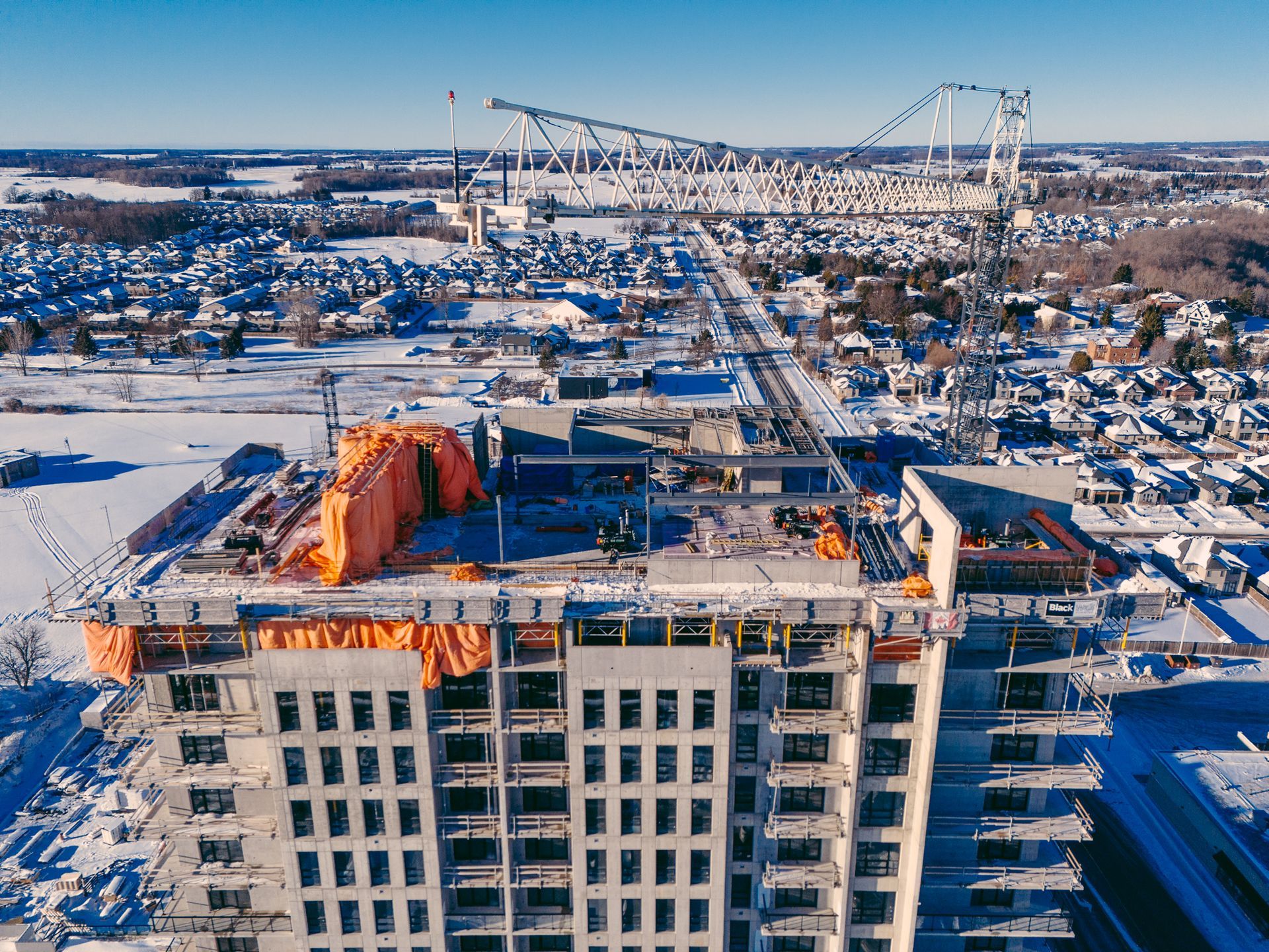 Snowy aerial view of a building under construction in a winter cityscape