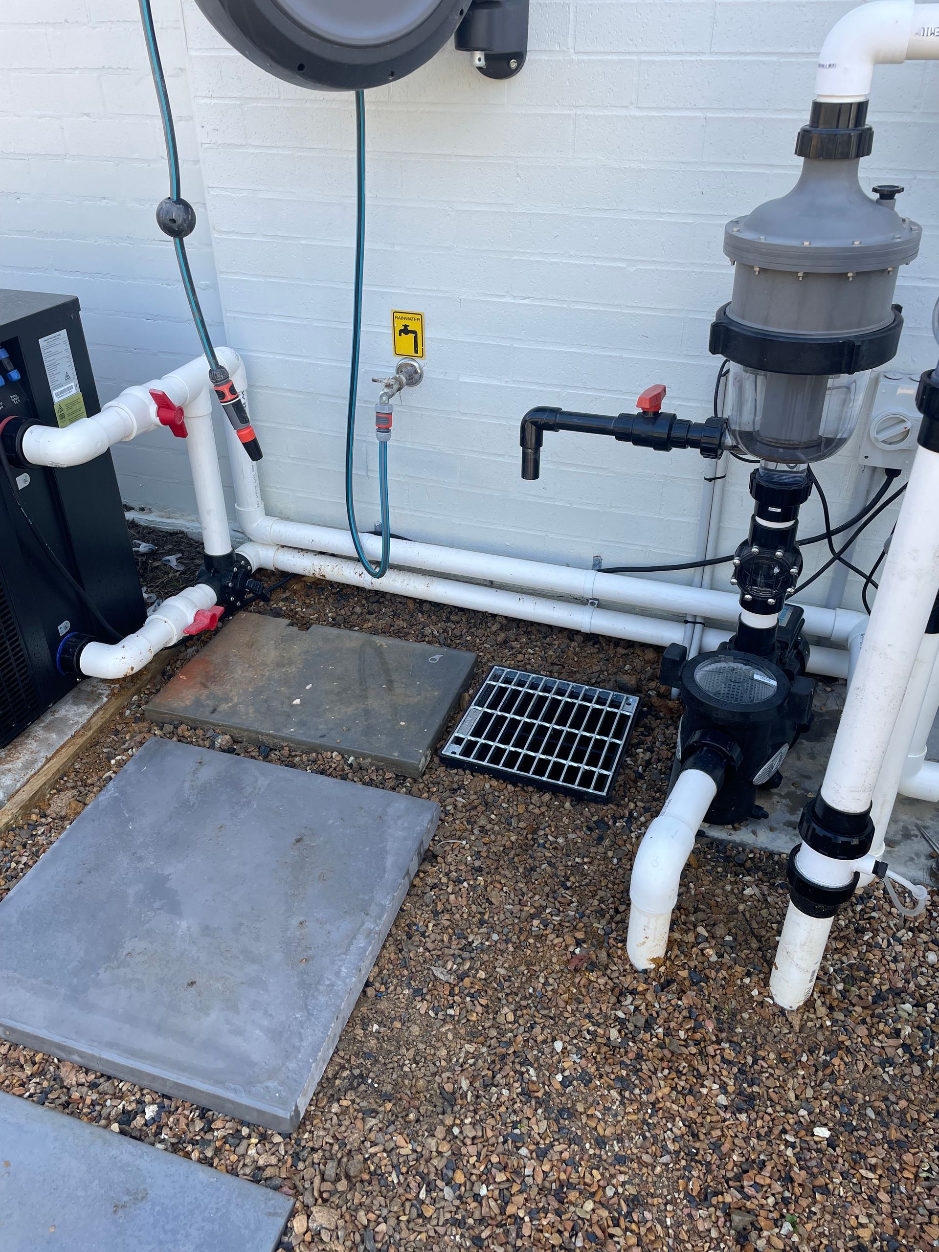 A bunch of pipes are sitting on the ground next to a wall.
