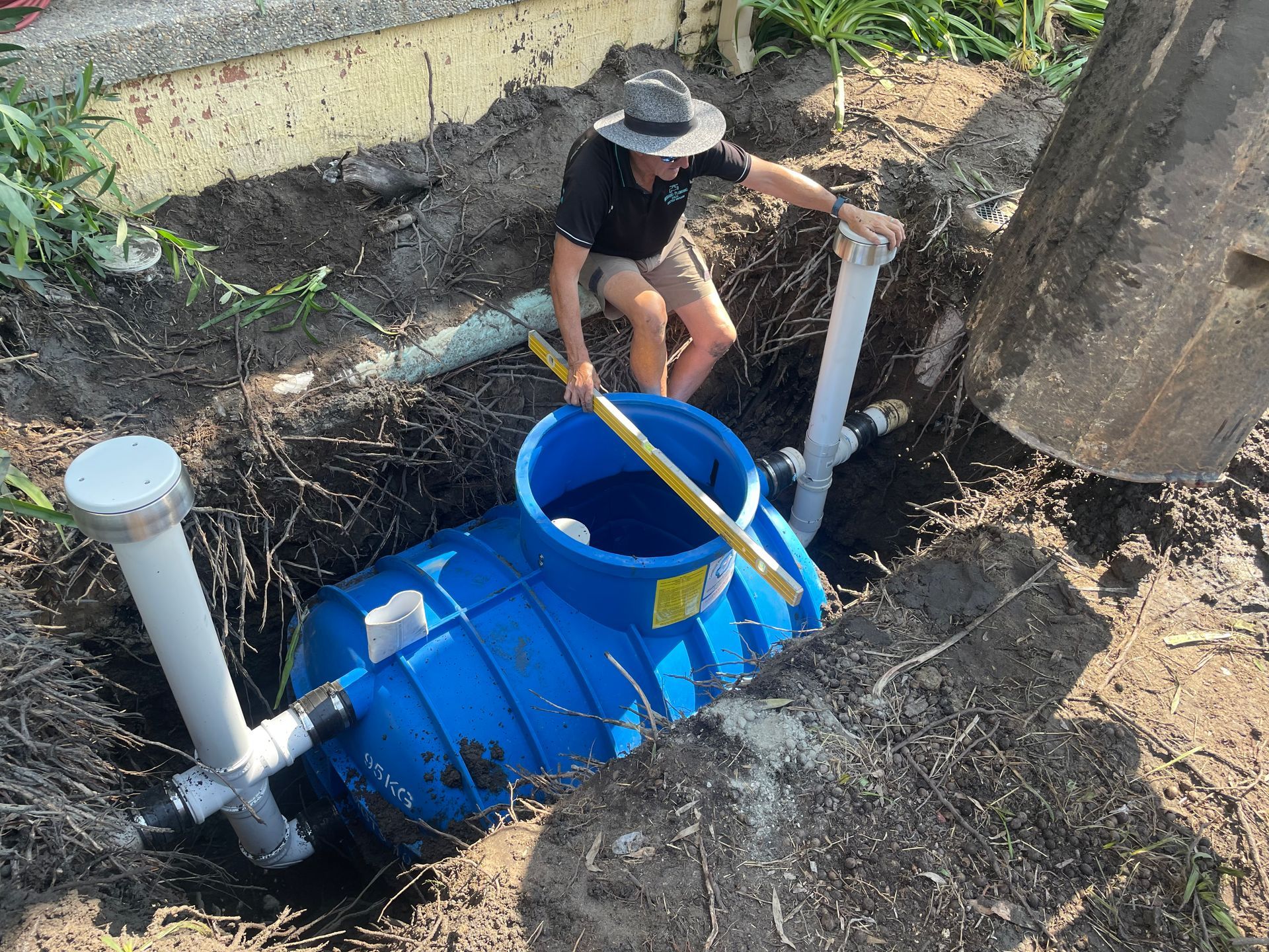 A man is standing in a hole next to a blue tank.