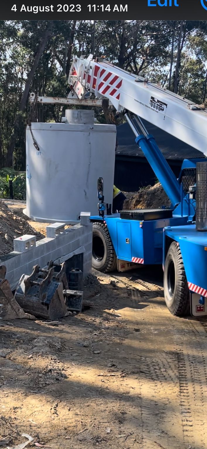 A blue and white construction vehicle is parked on a dirt road.