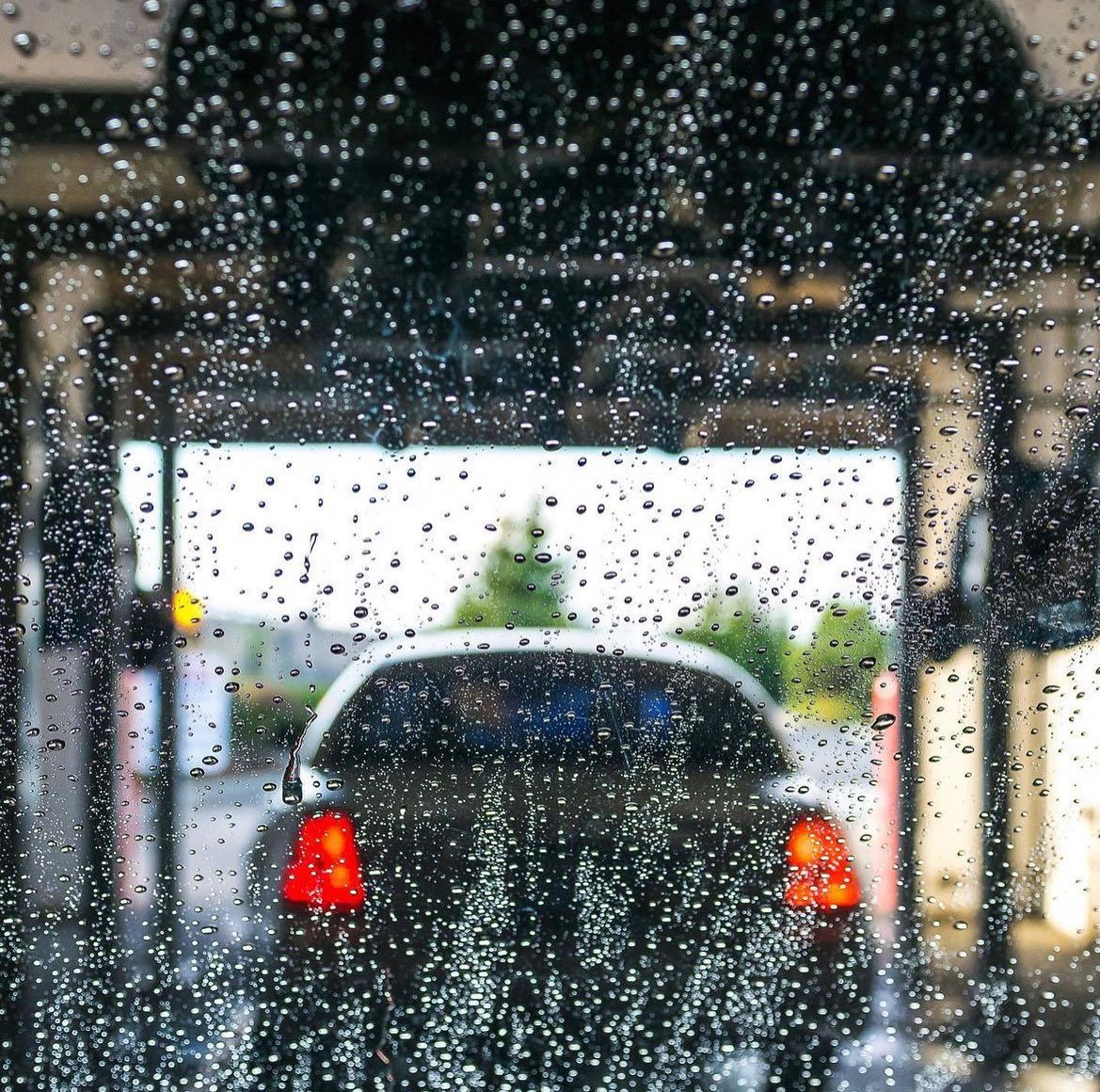 A car is going through a car wash in the rain.