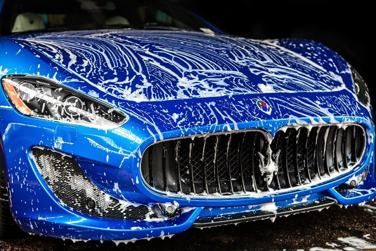 A blue sports car is covered in soap and water.