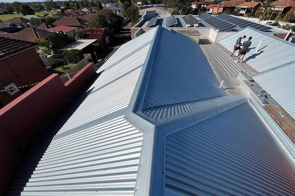 Two men are standing on the roof of a building.