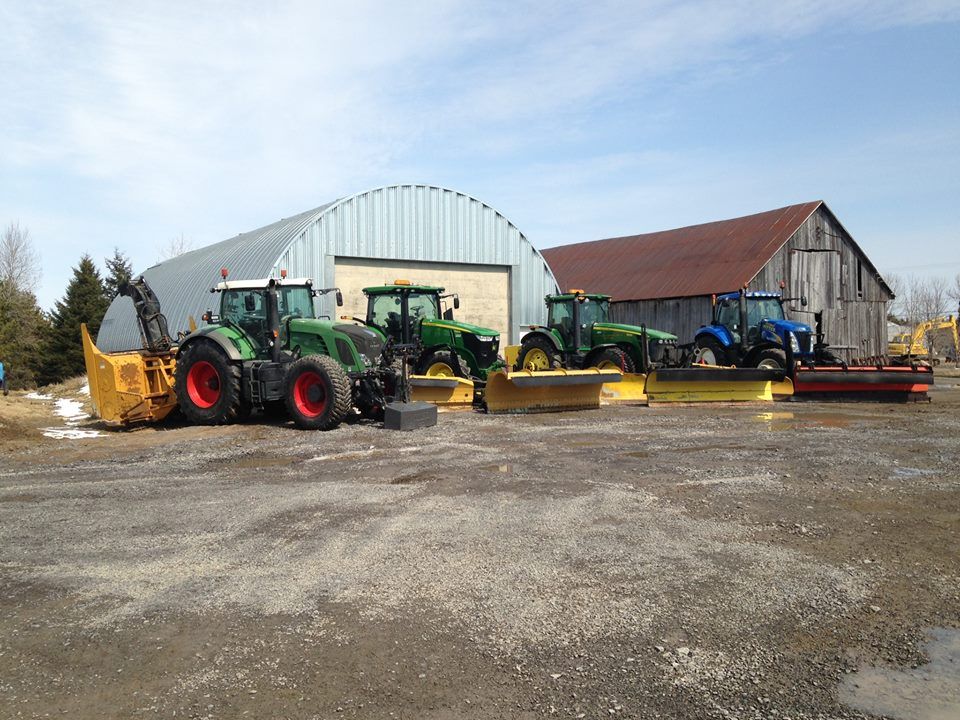 Un groupe de tracteurs est garé devant une grange.