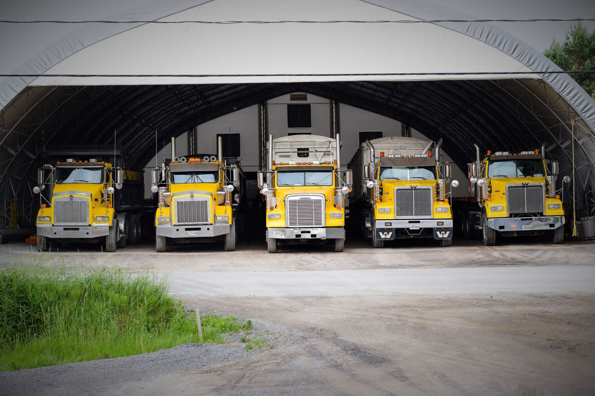 Une rangée de camions jaunes est garée dans un garage.