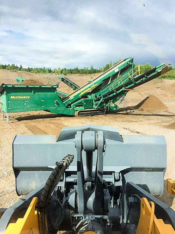 Une machine verte et jaune est assise sur un champ de terre.