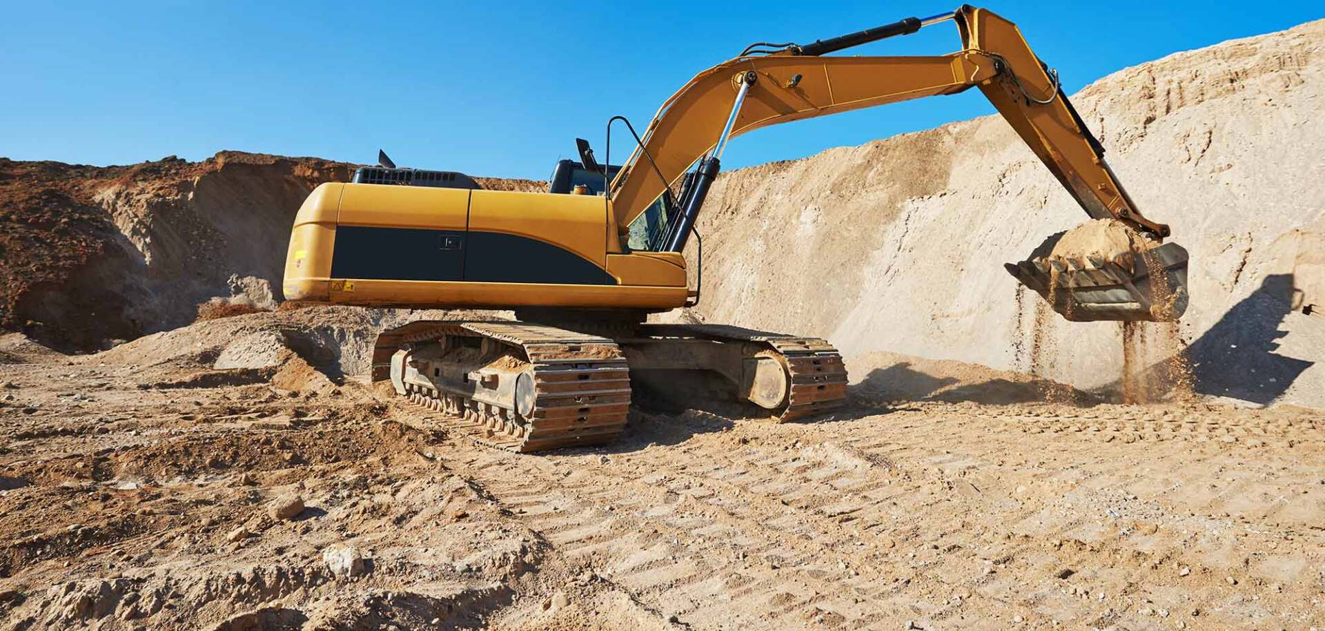 Une excavatrice jaune travaille dans un champ de terre