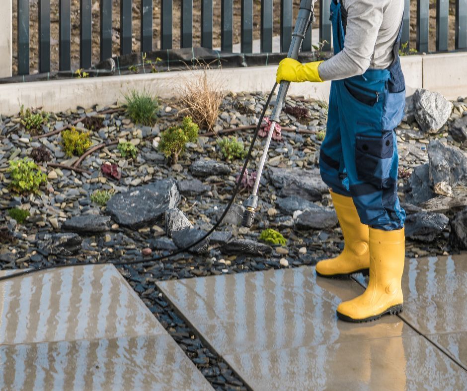 A man in yellow boots is cleaning a sidewalk with a high pressure washer safety.