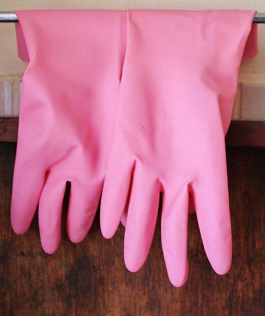 A pair of pink rubber gloves hanging on a towel rack