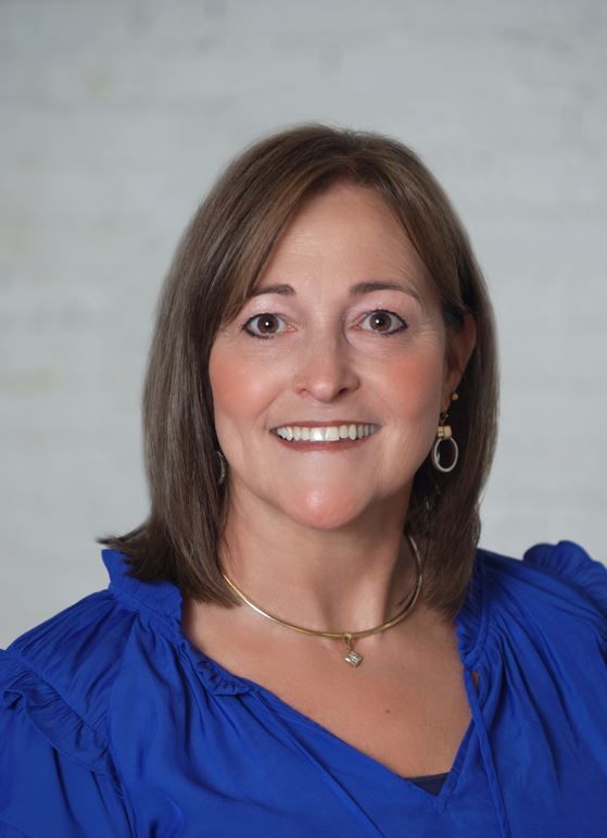 A close up of a woman wearing a necklace and smiling.