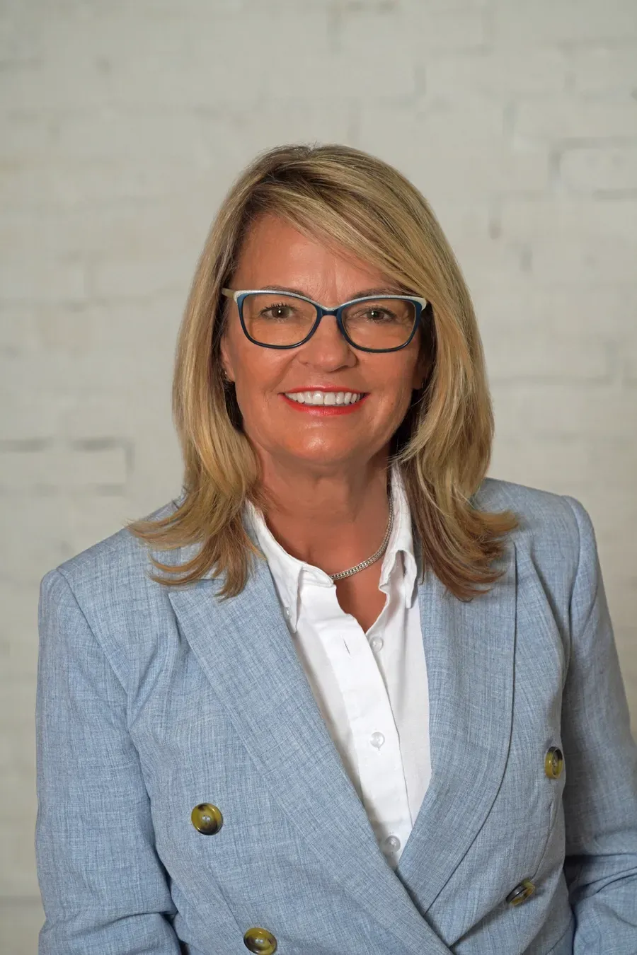 A woman wearing glasses and a black jacket is smiling for the camera.